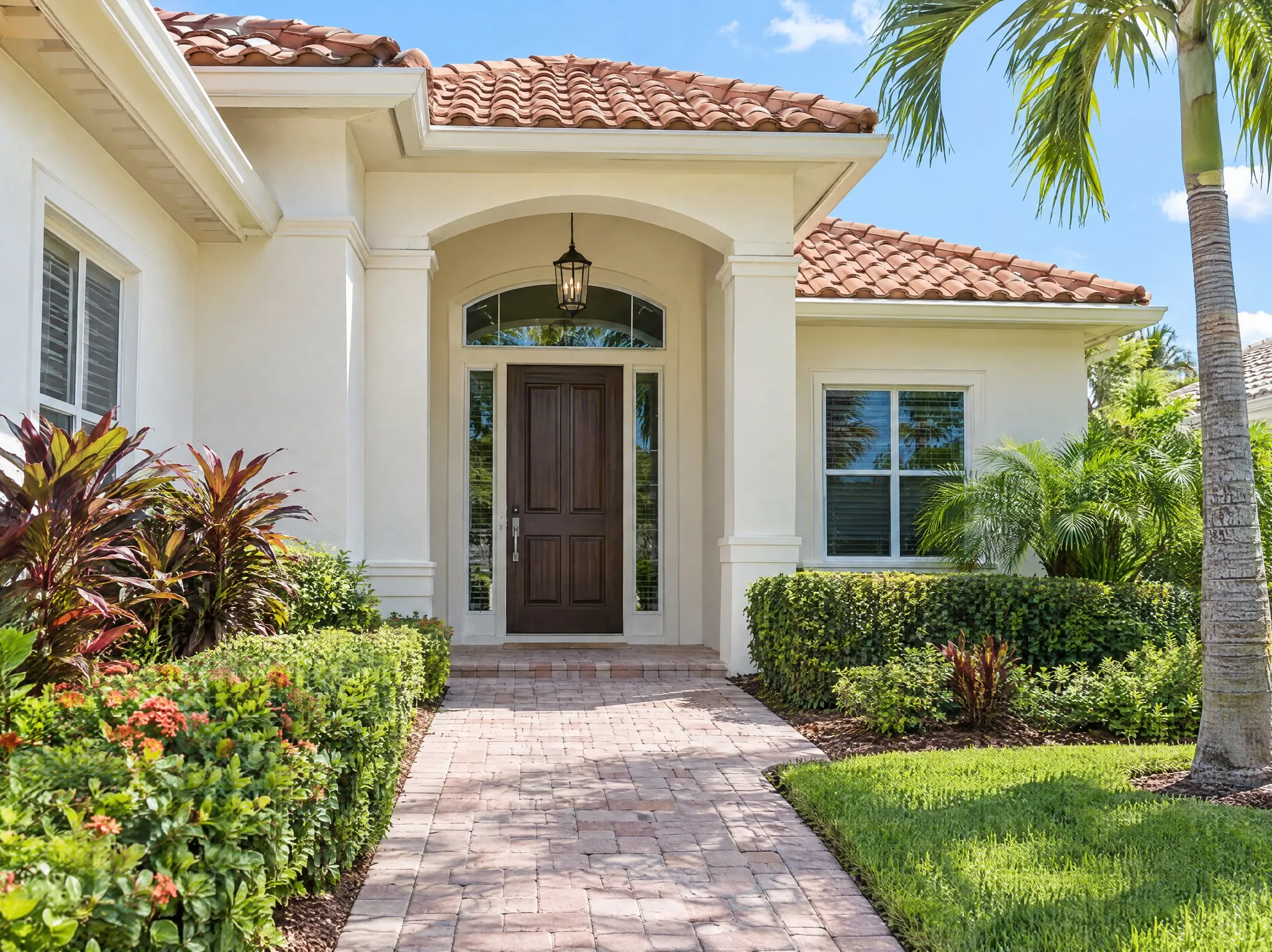 Clean front entry of a South Florida home with a wood door, paver walkway and tropical landscaping — get a free quote for exterior cleaning in Broward and Palm Beach County